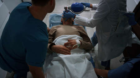 Medical workers carrying patient on gurney running emergency room. Professional team rolling sick...