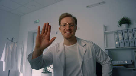 Smiling man therapist consulting remotely in clinic office close up pov video. Young physician...