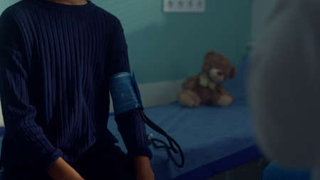 Smiling teen girl sitting clinic cabinet on medical consultation close up. Friendly caucasian doctor...