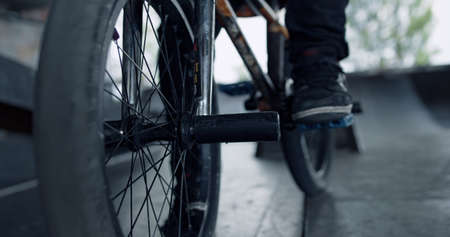 Man legs bmx bike at urban skate park. Close up bicycle wheels at skatepark. Closeup male legs on bmx bicycle pedal outdoors. Unknown man feet in sneakers. Active lifestyle activity summer concept.の写真素材