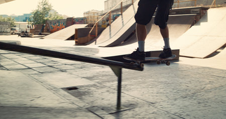 Extreme skateboarder riding on skateboard outside. Unknown active boy jumping on rail with skate board at skate park. Close up unrecognizable man legs in sneakers on board outdoors. Sport concept.の写真素材