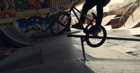 Young male hipster riding on bmx bike at urban space. Close up bmx rider performing dangerous tricks...