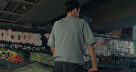 Sporty boy riding on scooter at urban skate park. Close up casual rider practicing outside. Close up...