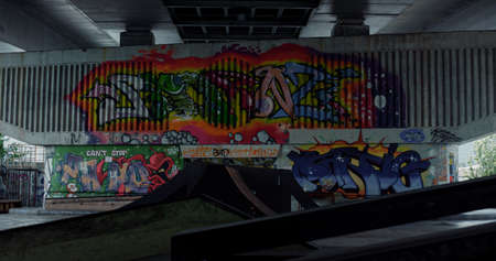 No people at skatepark with colorful graffiti on wall. Empty skate park with ramp for skateboarding....
