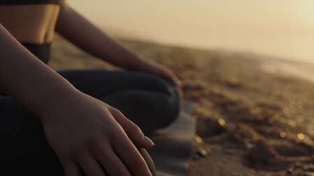 Unknown yoga woman body sitting lotus pose on sand beach close up. Slim girl meditating at summer...