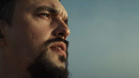 Portrait of focused bearded man looking forward on evening sunlight. Close up serious sportsman face...