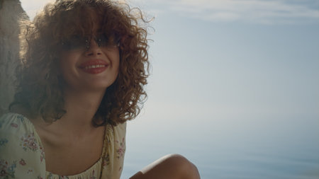 Cute positive girl laughing looking camera near calm blue sea close up. Portrait of happy young...