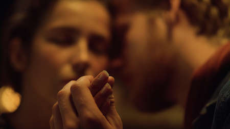 Lovely couple kissing sensual together on romantic evening holiday. Close up husband wife hold hands on honeymoon. Tender lovers flirt caress on valentines date. Relationship love intimacy concept.の写真素材