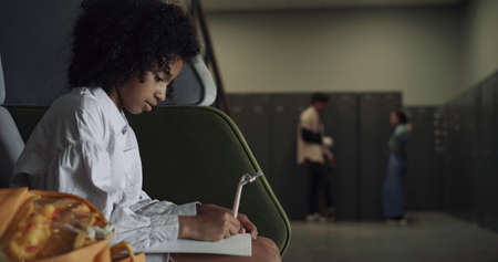 Serious african american teen student drawing sketches on school break. Pretty focused schoolgirl...