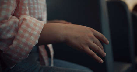 Unrecognized teenager gesturing hands talking with friends. Close up girl palms in school bus. Teen kid sitting schoolbus seat wearing stylish clothes. Public education transportation. Body languageの写真素材