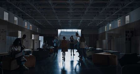 Silhouette cute little pupil rushing hall going to staircase. Elementary age schoolgirl with backpack passing playful schoolchildren walking upstairs. Lonely preteen girl leaving school alone.の写真素材