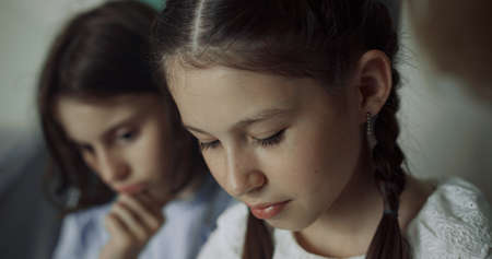Two pretty schoolgirls sitting together at school break close up. Portrait of cute serious preteen...