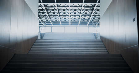 Empty bright school staircase interior. Light shining through glass window. Long clean stairway corridor heading towards lobby in large building. Lamps on ceiling. Modern construction concept.の写真素材