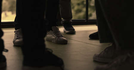 Group of students legs standing pushing in hall close up. Unrecognized schoolchildren offending outcast together in hallway. Angry school bullies fight indoors. Adolescent violence problem concept.の写真素材