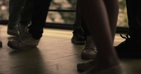 Closeup children legs standing group on hall floor. Diverse bullies pushing outcast. Unrecognized aggressive teenagers hurting punching classmate in school corridor. Adolescent violence problem.の写真素材