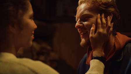 Two lovers enjoy each other by fireplace. Romantic couple hand touch face on evening date close up....