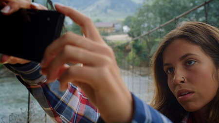 Traveler making selfie photo on mobile phone in summer nature. Portrait of serious girl posing...