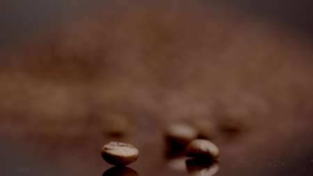 Pile of brown coffee grains close up background. Few perfect macro beans on foreground selective...