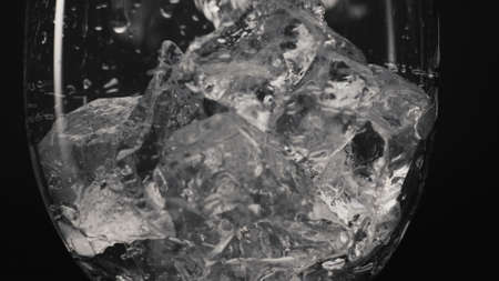 Ice cubes falling glass closeup slow motion. Frozen fragments pouring inside transparent dropped...