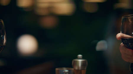 Fancy couple clinking wine glasses in romantic light restaurant bar. Two people celebrate anniversary together in cafe close up. Unknown lovers enjoy alcohol drinks in luxury pub. Dinner date concept.の写真素材