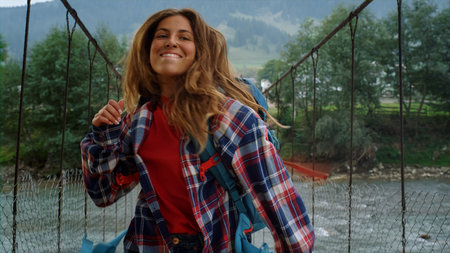 Traveler dance mountain hike on river bridge. Cheerful woman move body outside. Positive girl wear casual clothes backpack on nature explore tour. Hipster feel freedom in countryside. Leisure concept.の写真素材