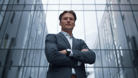 Portrait smiling confident businessman standing outside glass office building. Successful executive director financial analyst posing in suit at downtown district. Handsome lawyer looking in camera.の写真素材