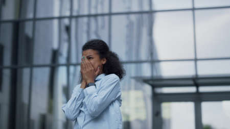 Depressed businesswoman crying at office building. Portrait of disappointed girl. Upset manager financial assistant breaking in tears in despair. Frustrated african american woman have work problems.の写真素材