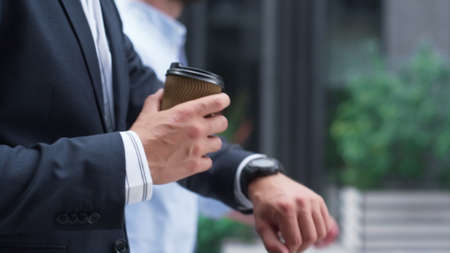 Confident businessman walking hold coffee downtown. Male hand with cup closeup. Unrecognized man...