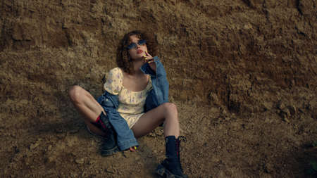 Confident sexy woman sitting sand seasoast in relaxed pose. Attractive young girl wearing cool...