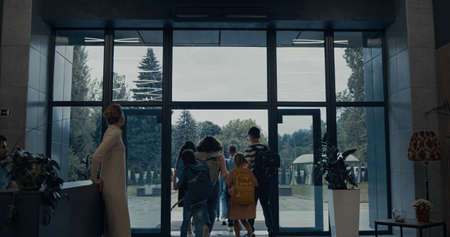 Group of joyful pupils leaving elementary school anticipating summer vacation. Smiling teacher...