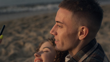 Happy couple posing for selfie photo on sea shore. Playful girl and guy taking selfie picture on...