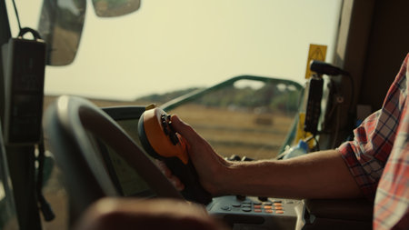 Farmer hands driving harvester closeup. Tractor operator controlling machinery in sunlight....