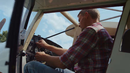 Serious pilot checking control panel steering wheel modern white airplane before flight close up....