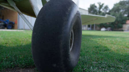 Closeup airplane wheel standing airfield grass. Black plane chassis on green aerodrome field in...