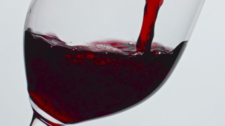 Closeup pouring red wine glass indoors. Alcoholic liquid filling wineglass super slow motion....