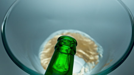 Bottled lager beer pouring vessel closeup. Sparkling cold craft beverage filling glass macro slow motion. Fizzy refreshing drink top view white background. Alcoholic unfiltered liquor conceptの写真素材