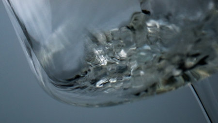 Closeup white wine bubbling splashing in goblet. Air bubbles flowing liquid. Golden fizzy beverage...