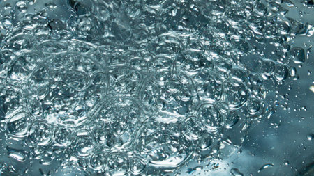 Small air bubbles rising up to smooth water surface closeup. Transparent mineral drink filling...