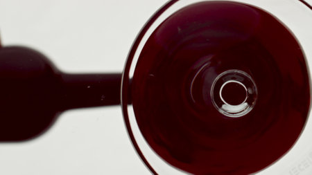 Bottom view red wine filling tumbler. Bordeaux alcoholic liquid inside wineglass macro. Rose merlot intoxicant drink glassware closeup. Refreshing liquor goblet establishing super slow motionの写真素材