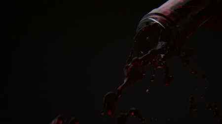 Gourmet red wine flowing from glass bottle in super slow motion close up. Stream luxury merlot pouring from transparent container on black background. Burgundy alcohol drink falling down splashing.の写真素材