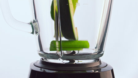 Green organic fruits vegetables falling blender cup in super slow motion close up. Pieces fresh...