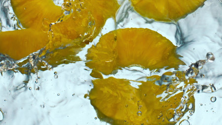 Closeup fresh tasty pineapple flowing transparent water on white background. Sweet vitamin ananas dropped into clear liquid in super slow motion. Natural ingredient for healthy delicious beverage.の写真素材