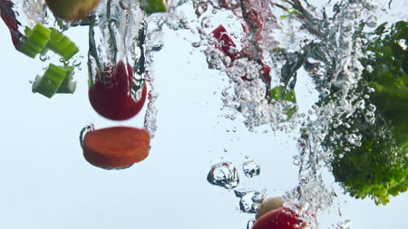 Organic fresh vegetable splashing clear water in super slow motion close up. Colorful ripe veggies falling into transparent liquid making bubbles. Raw carrot potato broccoli pepper tomato underwaterの写真素材