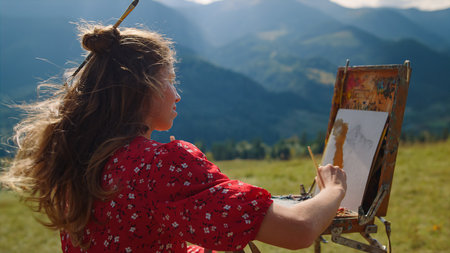 Closeup young woman painter drawing on green meadow sunny day. Creative girl painting picture of...