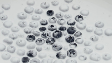 Natural tasty blueberry yogurt with ripe berries lying on creamy surface close up. Delicious vitamin...