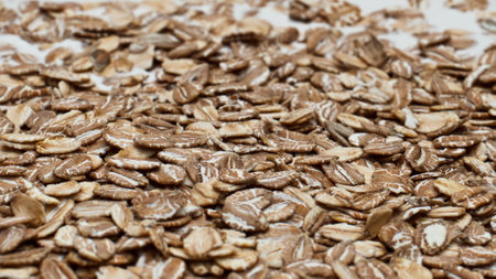Raw oat flakes dropped into natural yogurt for preparing healthy breakfast close up. Fresh cereal lying on dairy liquid rotating in super slow motion. Tasty organic nutrition for wellness concept.の写真素材