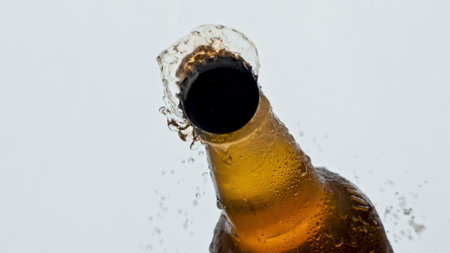 Opening glass ipa bottle closeup. Unfiltered beer splashing from condensating flask slow motion....