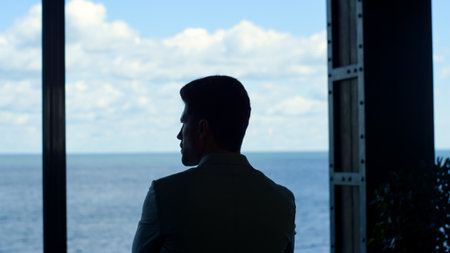 Silhouette businessman watching sea view big window. Back view of leader boss relaxing in luxury...