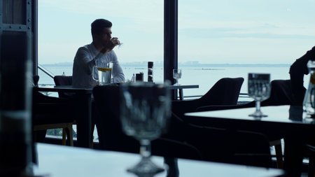 Charismatic man spending lunch time in luxury restaurant. Relaxed businessman drinking refreshing...