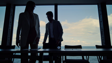 Business silhouettes shaking hands meeting in conference room. Two managers work on company...